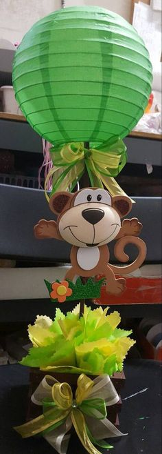 a green paper lantern with a monkey hanging from it's side next to some flowers