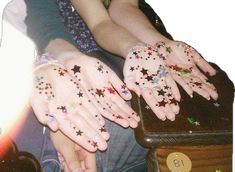 two hands with stars painted on them are sitting next to a suitcase and the other hand is covered in confetti