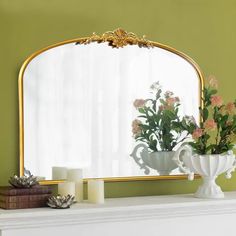 a mirror sitting on top of a mantle next to flowers