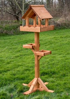 a wooden bird house on a stand in the grass