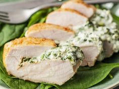 three slices of chicken with spinach and cream sauce on a green leafy plate