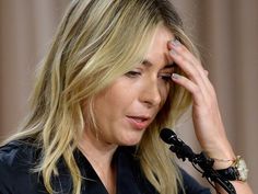 a woman holding her hand to her head while sitting in front of a microphone and looking off into the distance