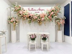 two white chairs with flowers on them in front of a wall