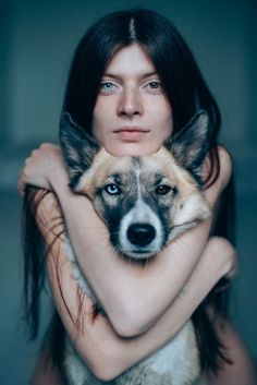 a woman holding a dog in her arms and looking at the camera with an intense look on her face