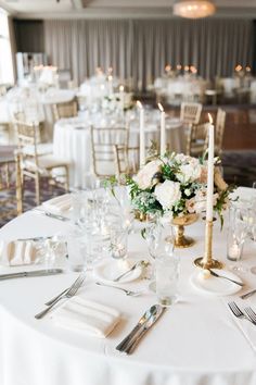 the table is set with white flowers and silverware