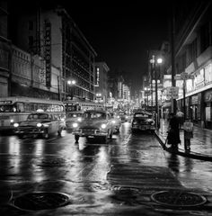 black and white photograph of cars driving down the street at night