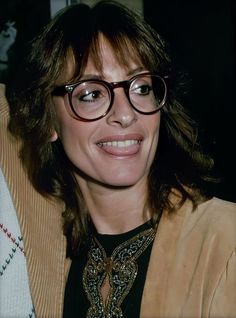 a woman wearing glasses is smiling at the camera