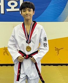 a young boy standing on top of a yellow floor holding a black and white belt