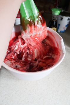 a person is scooping something out of a bowl with red and white liquid in it