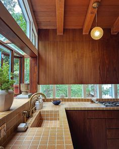 a kitchen with wood paneling and tile counter tops in front of a large window