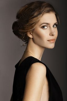 a woman in a black dress posing for the camera with her hair up and eyes closed