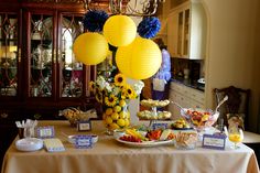 a table topped with lots of food next to a chandelier filled with yellow paper lanterns