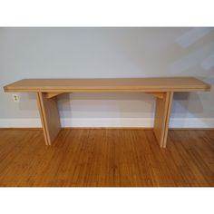 a wooden table sitting on top of a hard wood floor next to a white wall