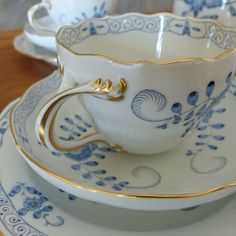 a tea cup and saucer sitting on top of a plate with gold trimmings