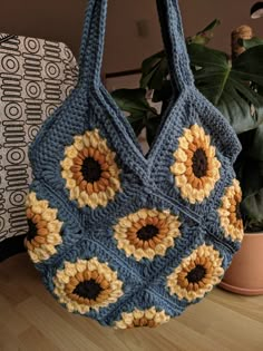 a blue crocheted bag with sunflowers on it sitting next to a potted plant