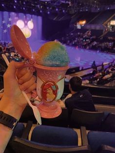 a person holding up an ice cream cup with spoons in it at a sporting event