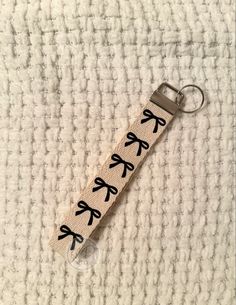 a keychain with black bows on it sitting on top of a white blanket