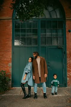 a man and woman standing in front of a green door with a child next to them