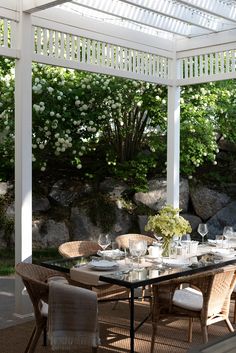 an outdoor dining table set for four under a white pergolan