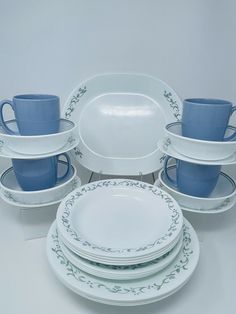 a white table topped with lots of blue plates and cups on top of each other