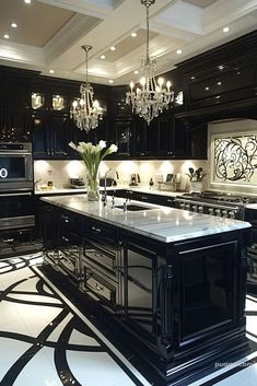 a black and white kitchen with chandelier, marble counter tops and an island