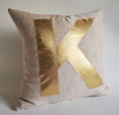 a gold letter k pillow on a white background with the letter k painted on it