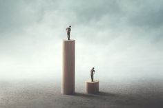 two people standing on top of pillars in the middle of a foggy sky,