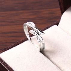 a silver ring sitting on top of a wooden table next to a white cloth covered box