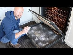 a man kneeling down in front of an open oven with something on the bottom shelf