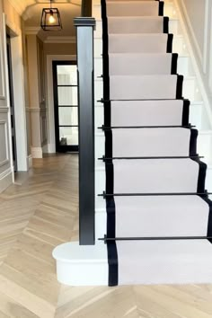 a staircase with white carpet and black handrails