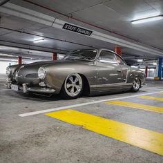 an old silver car parked in a parking garage next to a yellow caution sign that says start parking