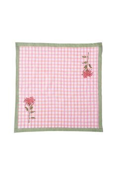 a pink and white checkered table cloth with flowers on the front, green border