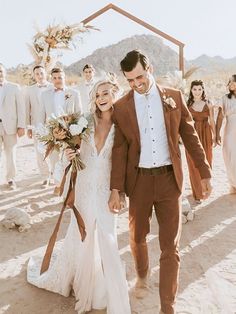 a bride and groom walking down the beach with their bridal party in the background