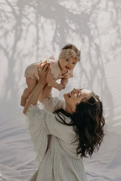 a woman holding a baby up in the air