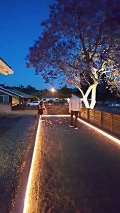 two people standing on the side of a road at night