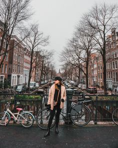 a woman standing next to her bike on the street in front of some parked bicycles