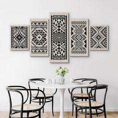 a white table with four chairs around it in front of a black and white wall