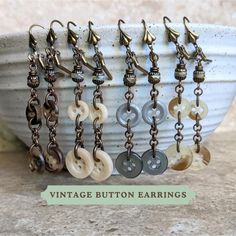 a bunch of buttons and chains are hanging from a bowl with the words vintage button earrings on it