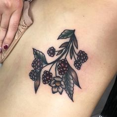 a close up of a woman's stomach with berries and leaves tattooed on it