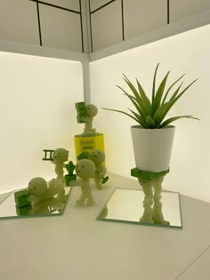 three small toy animals and a potted plant on a white table with mirrored mirrors