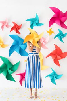 a woman standing in front of colorful origami paper stars on a wall with her hands behind her head