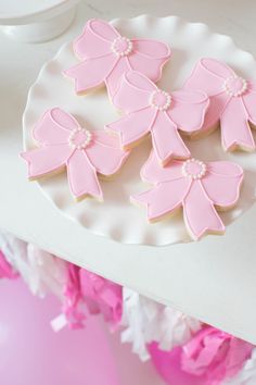 pink decorated cookies sitting on top of a white plate