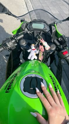 a person's hand on the handlebars of a green motorcycle