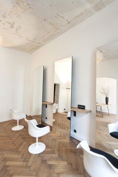 an empty room with white chairs and mirrors