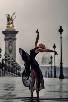 a ballerina is dancing in the rain with her arms stretched out and legs spread wide