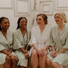 four bridesmaids in robes sitting on the floor laughing and looking at each other