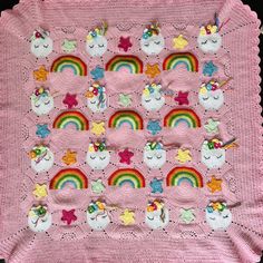 a pink crocheted blanket with rainbows, stars and clouds in the center