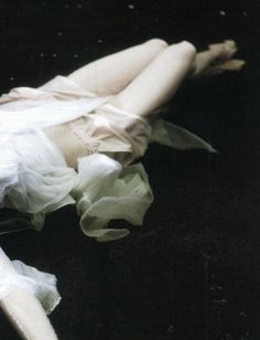 a woman laying on the ground wearing a white dress with ruffles around her body