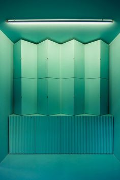 an empty room with blue walls and green lighting on the ceiling is lit by a dim light