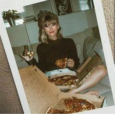 a woman sitting on a couch holding two pizzas